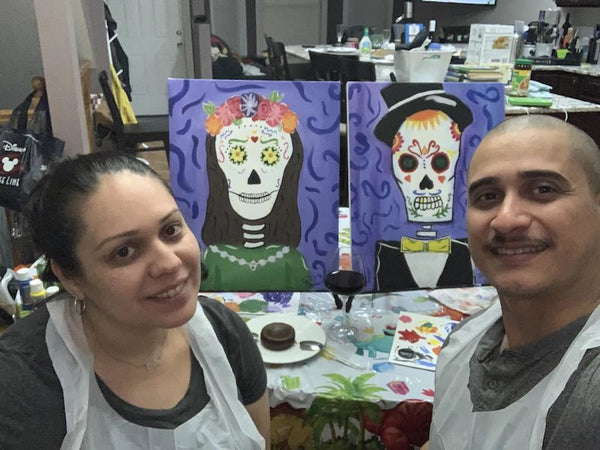 Couple with their finished Life is Sweet sugar skull date night diptych and a glass of wine