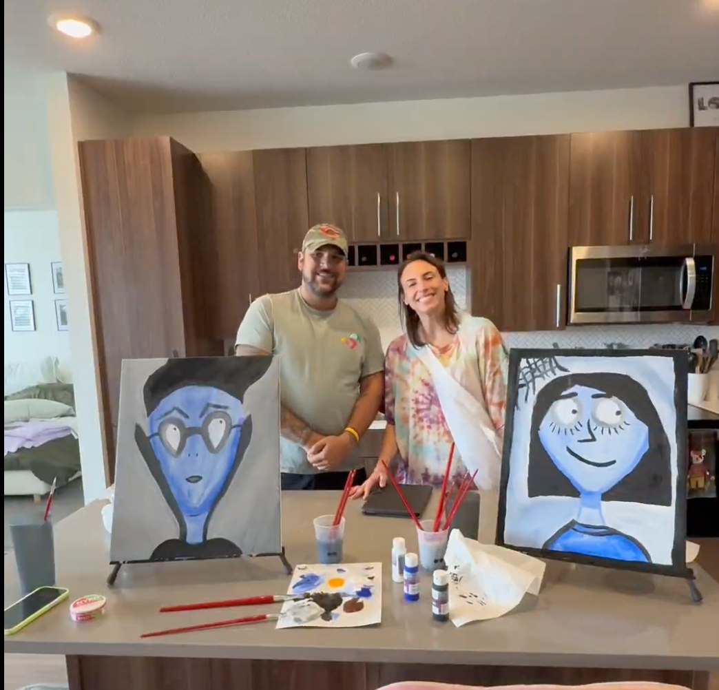 Couple with their finished Spooky Selfies paintings in their kitchen