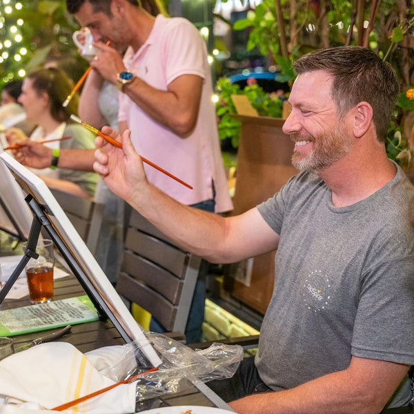 Man smiling as he paints on a canvas